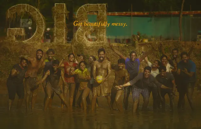 Get beautifully messy. A group covered in mud, cheering in shallow water.