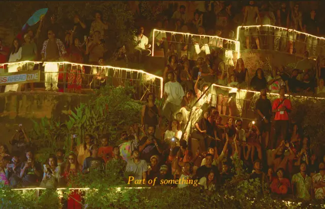 Part of something. A crowd on terraced steps strung with warm lights.
